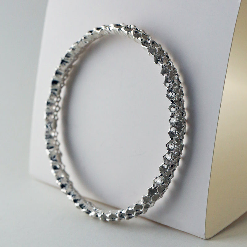 Handmade Sterling silver bangle bracelet with an organic honeycomb-inspired texture, crafted from sustainable materials.