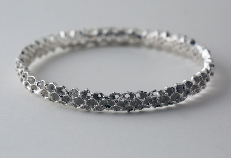 Sterling Silver bangle bracelet featuring a detailed honeycomb-inspired texture, displayed on a plain white background.